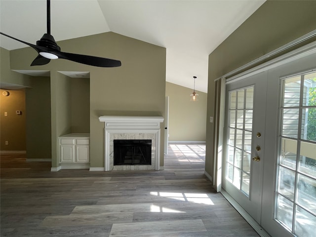 unfurnished living room with a tile fireplace, french doors, lofted ceiling, and light wood-type flooring