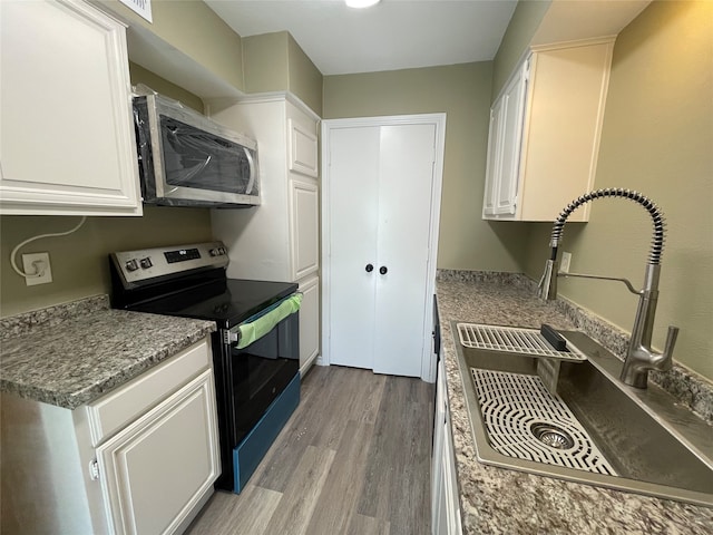 kitchen featuring light wood-type flooring, white cabinetry, black range with electric stovetop, and sink