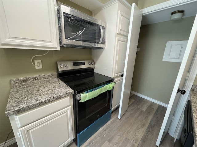 kitchen featuring light stone counters, white cabinets, light wood-type flooring, and appliances with stainless steel finishes