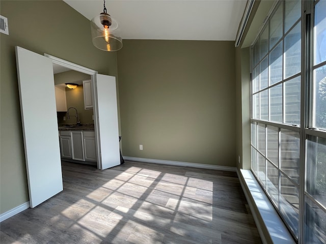 empty room featuring hardwood / wood-style flooring, sink, and vaulted ceiling