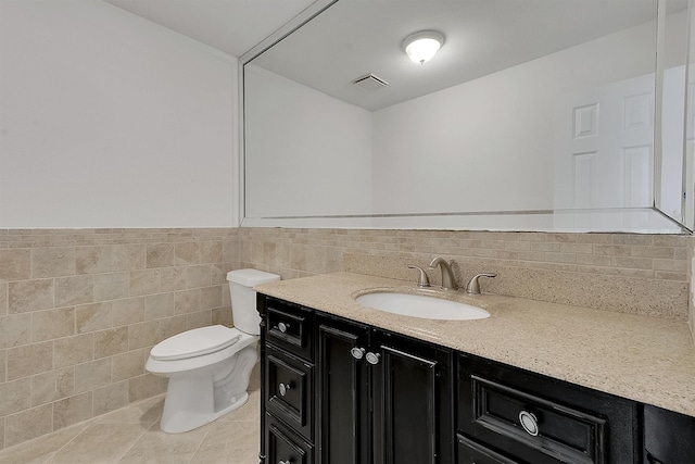 bathroom featuring tile patterned flooring, tile walls, vanity, and toilet