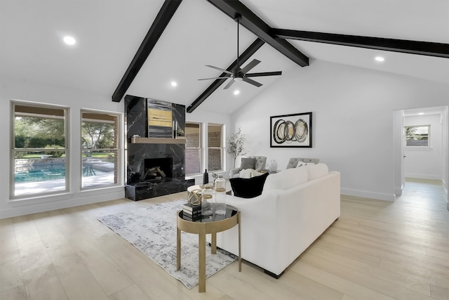 living room featuring high vaulted ceiling, ceiling fan, light hardwood / wood-style floors, a high end fireplace, and beam ceiling