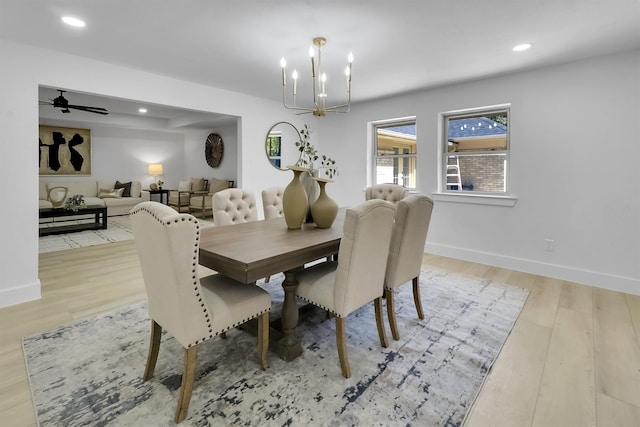 dining area with ceiling fan with notable chandelier and light hardwood / wood-style floors