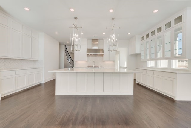 kitchen with dark wood-type flooring, light countertops, a sink, and wall chimney range hood