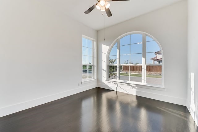 empty room with baseboards, dark wood finished floors, and a ceiling fan