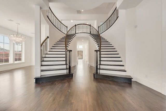 staircase with arched walkways, a high ceiling, wood finished floors, and baseboards