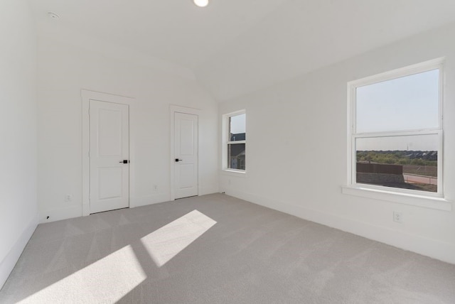 interior space with light colored carpet, vaulted ceiling, and baseboards