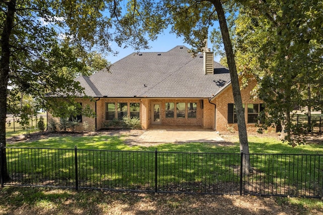 rear view of house with a fenced backyard, a chimney, a yard, a patio area, and brick siding