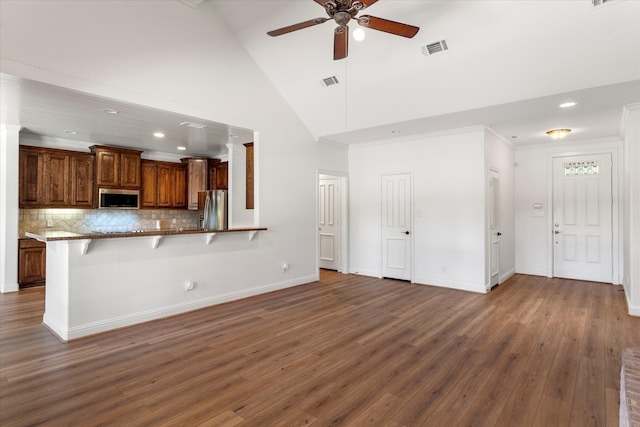 kitchen with stainless steel appliances, tasteful backsplash, kitchen peninsula, a breakfast bar area, and high vaulted ceiling