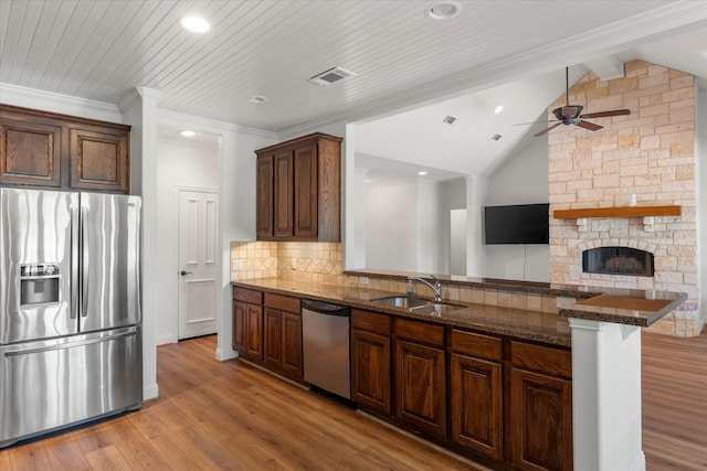 kitchen featuring appliances with stainless steel finishes, lofted ceiling with beams, kitchen peninsula, sink, and backsplash