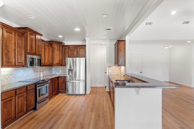 kitchen with light wood-type flooring, backsplash, a breakfast bar, crown molding, and appliances with stainless steel finishes