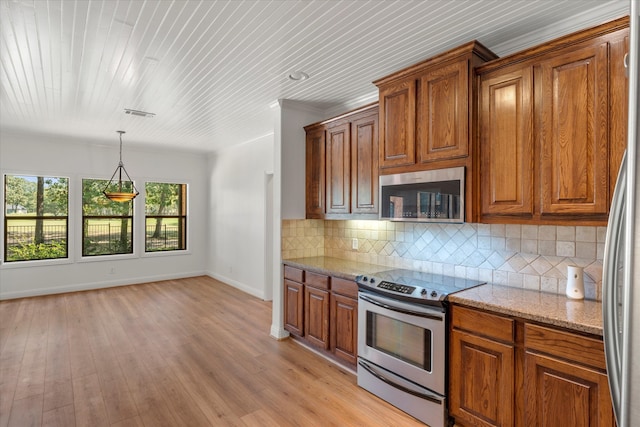 kitchen featuring decorative light fixtures, light stone counters, light hardwood / wood-style flooring, backsplash, and appliances with stainless steel finishes