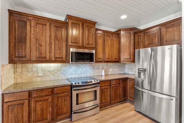 kitchen featuring appliances with stainless steel finishes, light wood-type flooring, crown molding, light stone counters, and backsplash