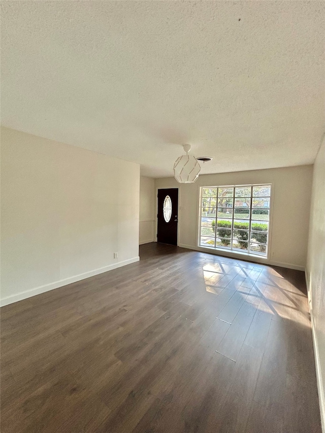 spare room featuring a textured ceiling and dark hardwood / wood-style flooring