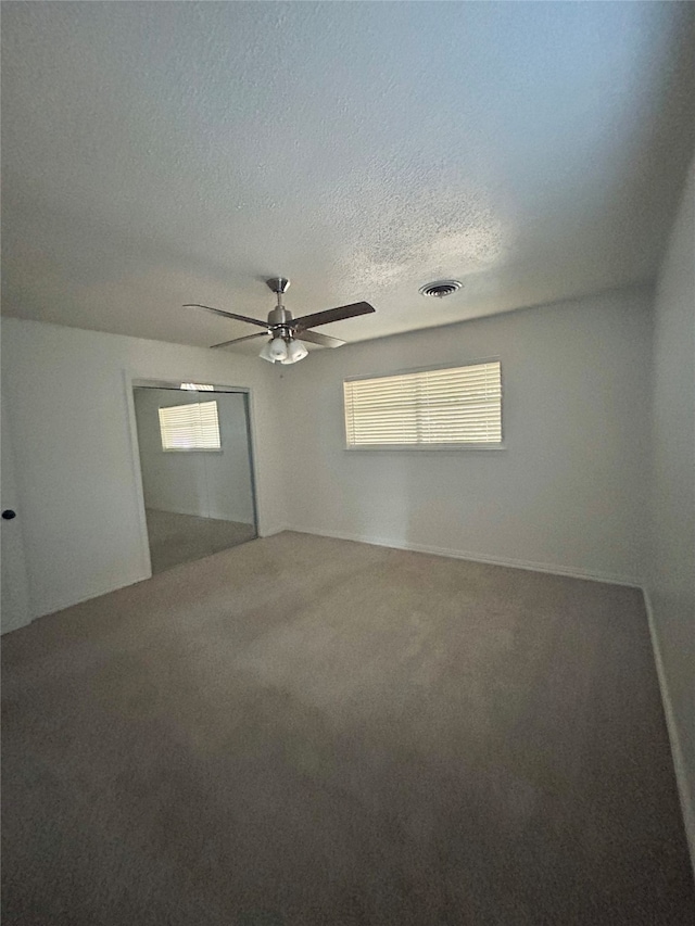 empty room with ceiling fan, carpet, and a textured ceiling