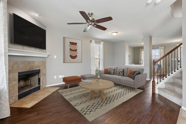 living room with dark wood-type flooring, a wealth of natural light, and a tile fireplace