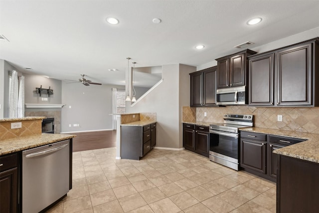 kitchen featuring light tile patterned floors, pendant lighting, appliances with stainless steel finishes, and dark brown cabinets