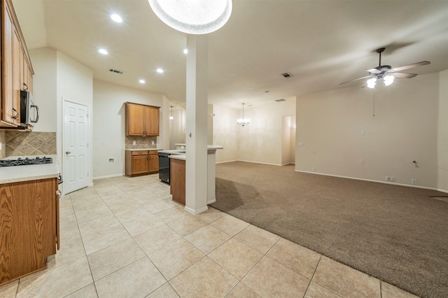 kitchen featuring light carpet, pendant lighting, ceiling fan with notable chandelier, and tasteful backsplash