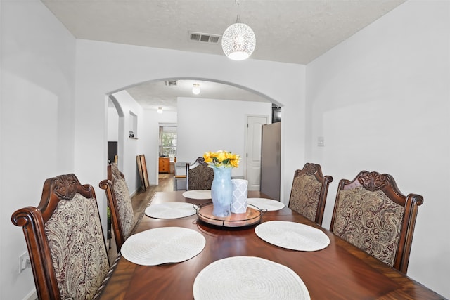 dining room with wood-type flooring and a textured ceiling