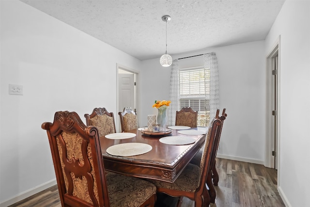 dining area with dark wood-type flooring and a textured ceiling