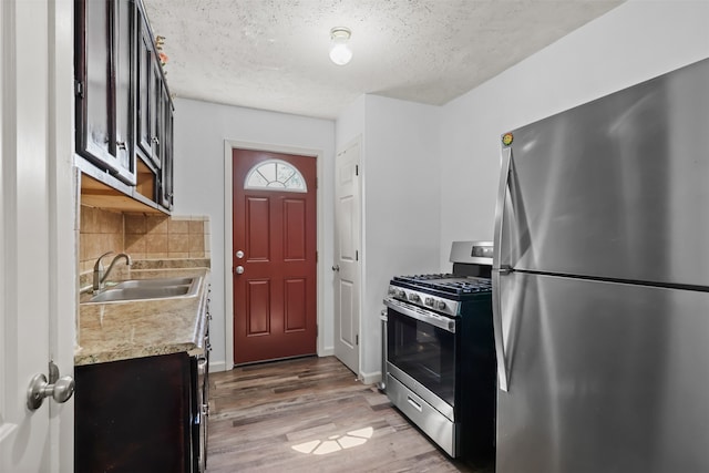 kitchen featuring tasteful backsplash, hardwood / wood-style floors, sink, stainless steel appliances, and a textured ceiling