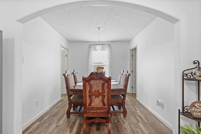 dining area featuring wood-type flooring and a textured ceiling