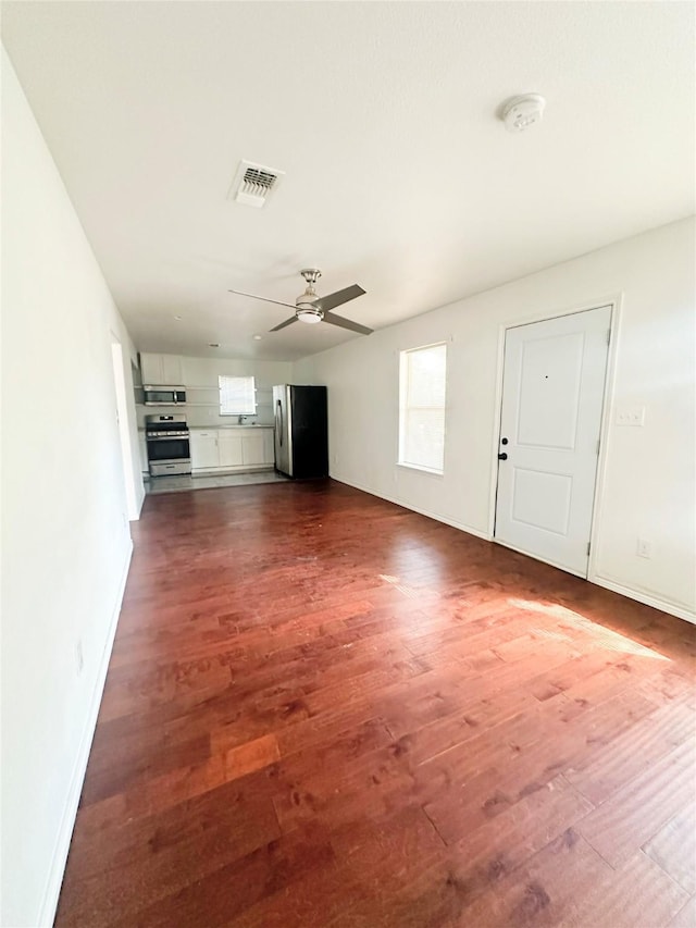 729 N Ruddell St, Denton, TX 76209 - unfurnished living room with dark wood-style floors, ceiling fan, and baseboards