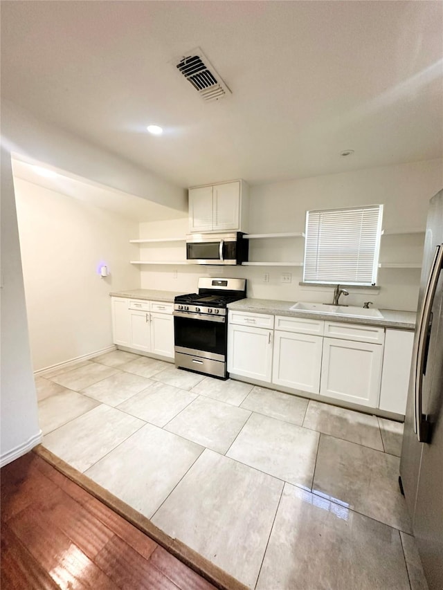 729 N Ruddell St, Denton, TX 76209 - kitchen with open shelves, a sink, appliances with stainless steel finishes, and white cabinets
