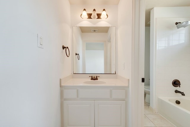 full bathroom with tile patterned flooring, tiled shower / bath, vanity, and toilet