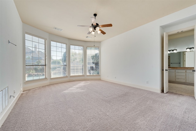 spare room with plenty of natural light, light colored carpet, and ceiling fan