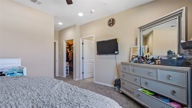 bedroom featuring a closet, a walk in closet, carpet flooring, and ceiling fan