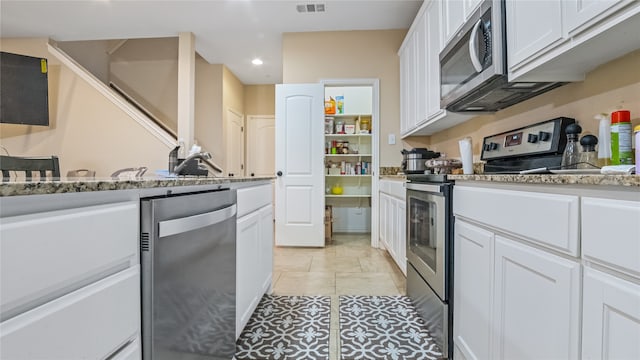 kitchen featuring light tile patterned flooring, light stone counters, stainless steel appliances, and white cabinets