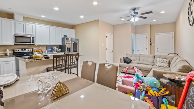 kitchen with ceiling fan, light stone countertops, appliances with stainless steel finishes, and white cabinetry