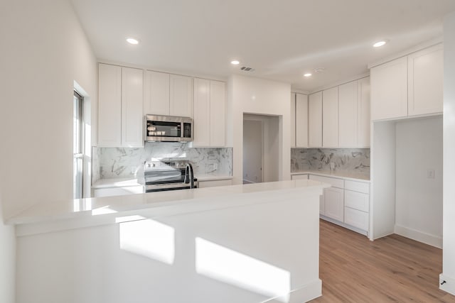 kitchen with light hardwood / wood-style flooring, white cabinets, and stainless steel appliances