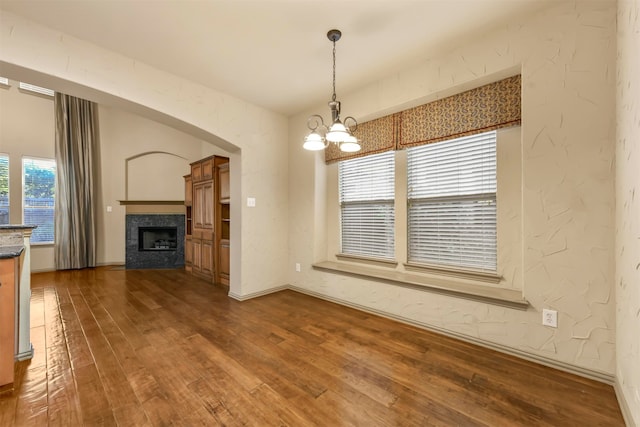 unfurnished living room featuring plenty of natural light, hardwood / wood-style floors, and an inviting chandelier