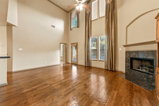 unfurnished living room with a high end fireplace, crown molding, hardwood / wood-style floors, and a healthy amount of sunlight