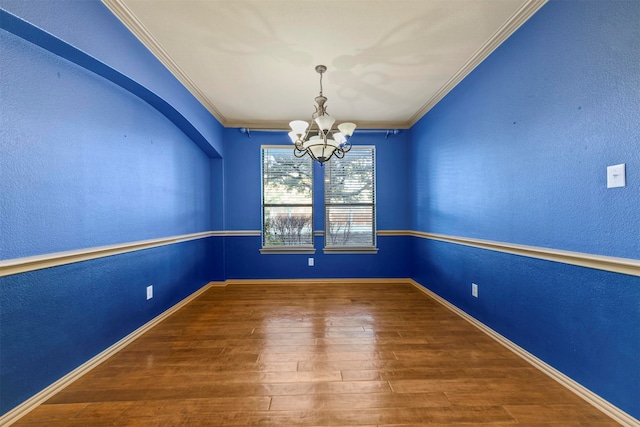 unfurnished room with a notable chandelier, ornamental molding, and hardwood / wood-style flooring