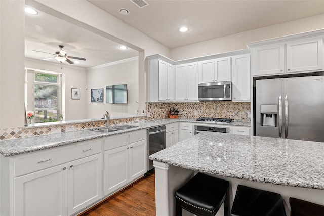 kitchen featuring white cabinets, appliances with stainless steel finishes, sink, and a breakfast bar area