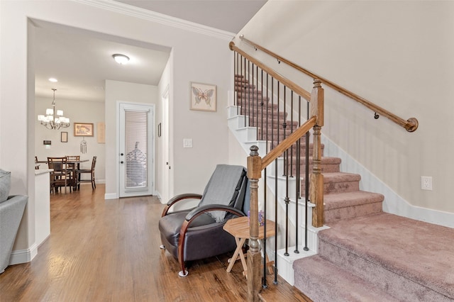 staircase with a chandelier, wood-type flooring, and crown molding