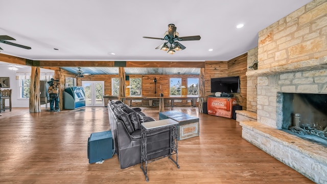 living room featuring a stone fireplace, wood-type flooring, and french doors