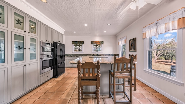 kitchen featuring gray cabinets, light stone counters, black refrigerator, and double oven