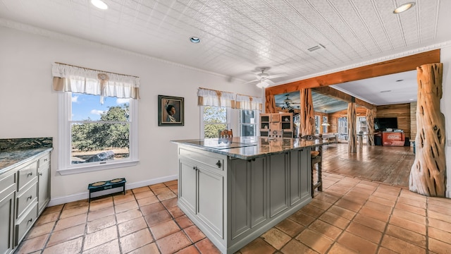 kitchen with dark stone countertops, a breakfast bar area, a kitchen island, and a wealth of natural light