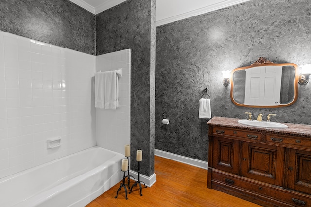 bathroom featuring hardwood / wood-style flooring, ornamental molding, vanity, and  shower combination