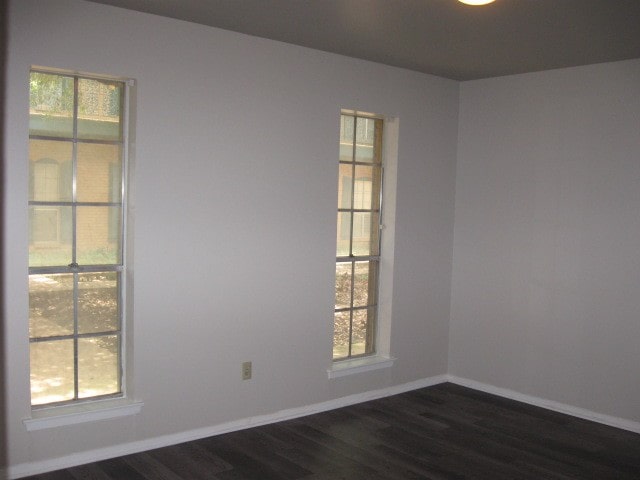 spare room featuring dark wood-type flooring and a healthy amount of sunlight