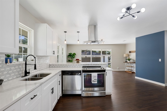 kitchen with appliances with stainless steel finishes, sink, island range hood, kitchen peninsula, and white cabinetry