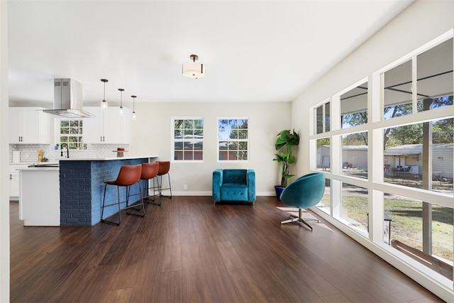 interior space with island exhaust hood, white cabinets, a healthy amount of sunlight, and pendant lighting