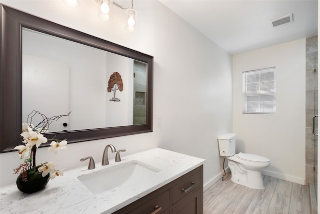 bathroom featuring toilet, an enclosed shower, vanity, and wood-type flooring