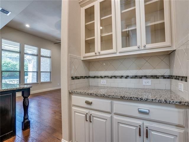 kitchen featuring white cabinetry, dark wood-type flooring, tasteful backsplash, and light stone countertops