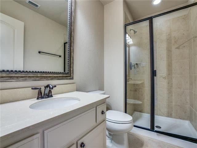 bathroom with a shower with shower door, vanity, and toilet