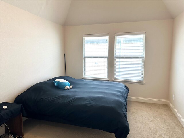 bedroom featuring vaulted ceiling and light colored carpet